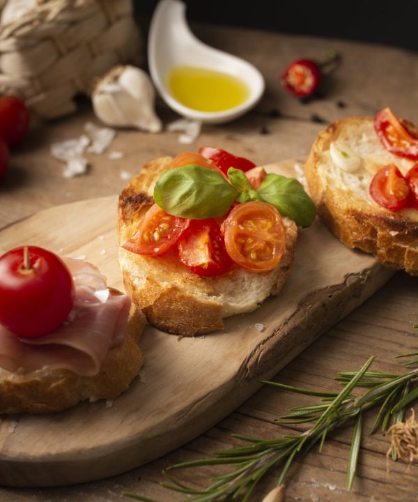 high-angle-bruschettas-with-prosciutto-tomatoes-cutting-board